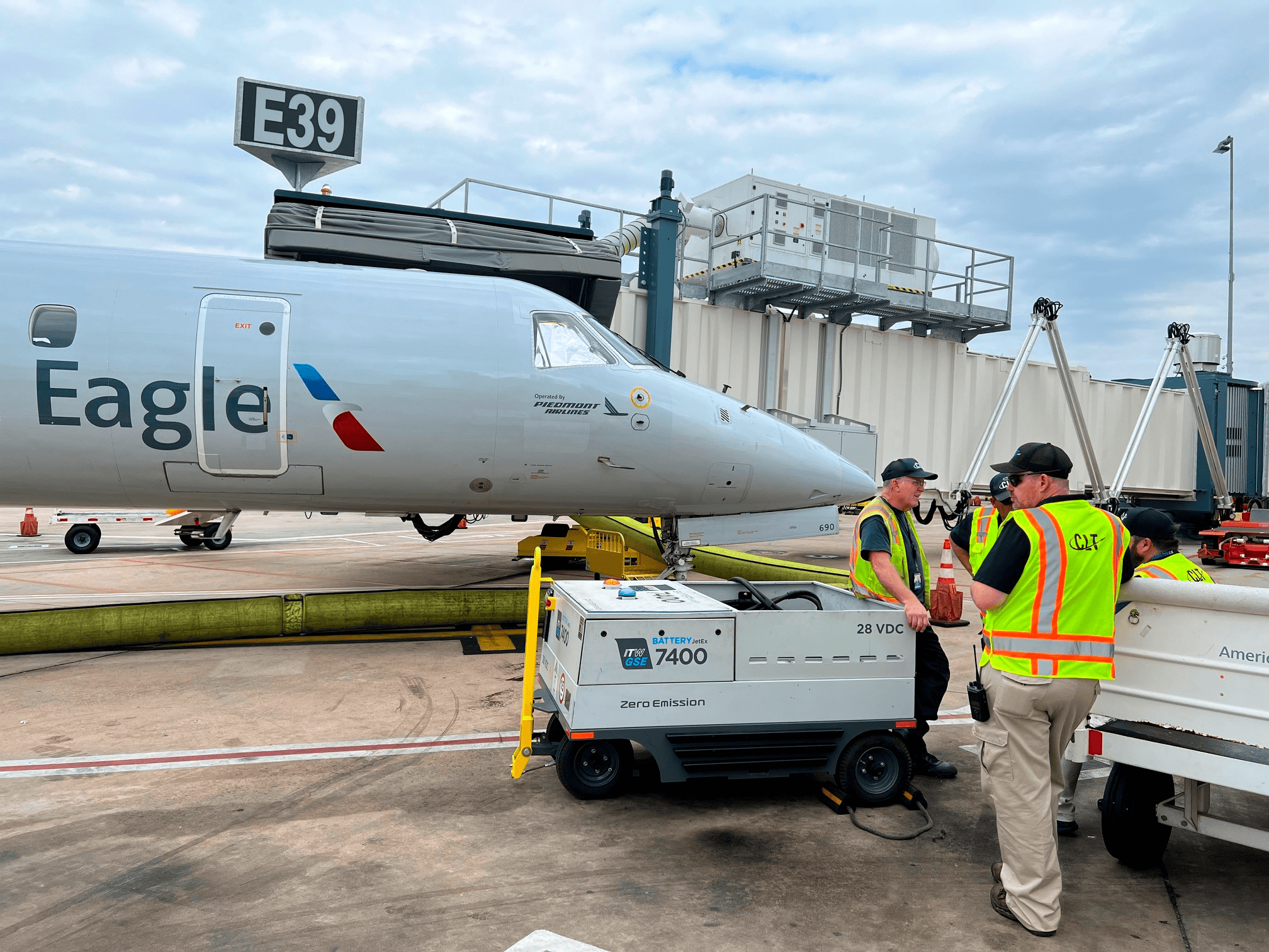 the itw gse 7400 jetex battery driven located in the airport of charlotte in north carolina in the us. next to the jetex you see an aircraft and two ground handlers.