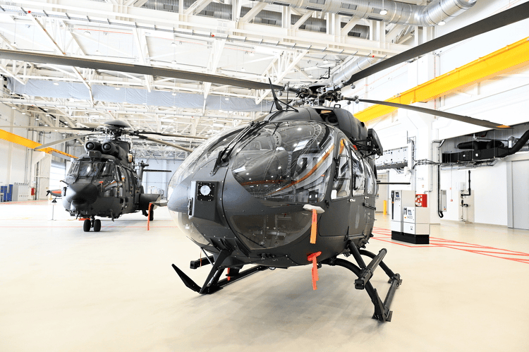 two helicoptors in a hangar in Hungary and in the background your see an itw gse 1400 ground power unit and an itw gse 2400 ground power unit.