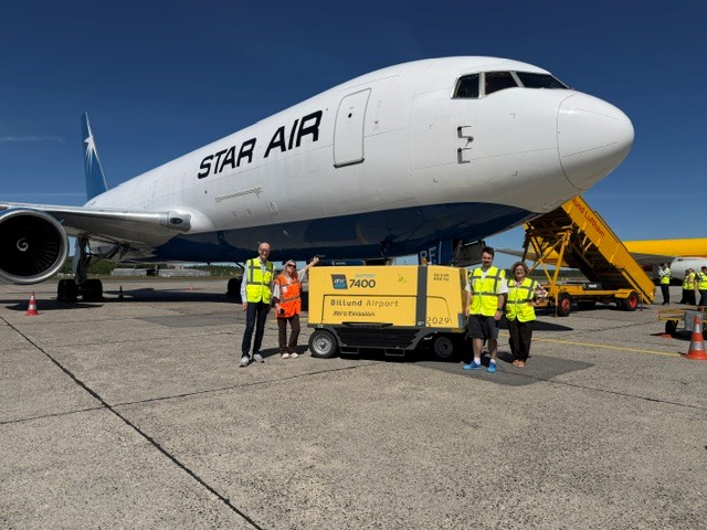 four of the itw gse staff in the spare part team next to an yello 7400 egpu in front of an aircraft in billund airport